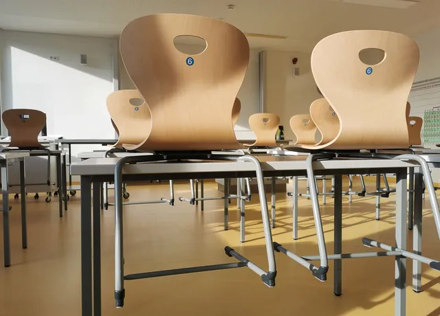 Klassenraum mit hochgestellten Stühlen nach Unterrichtsschluss