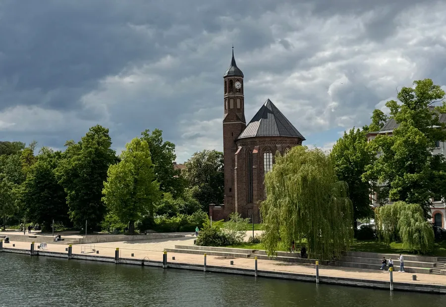 Backsteinkirche hinter einer Uferpromenade